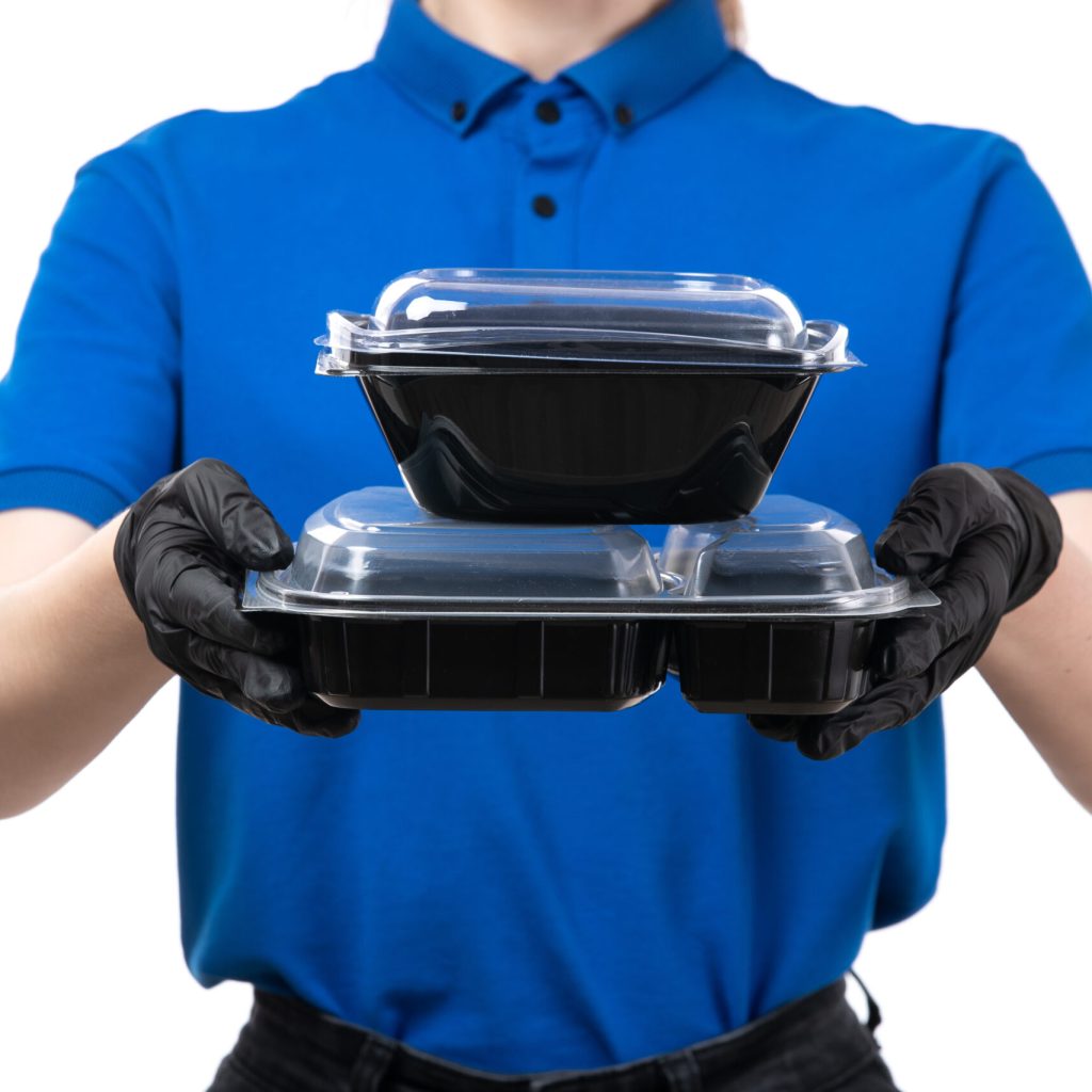 front view young female courier blue uniform black gloves black mask holding food delivery bowls