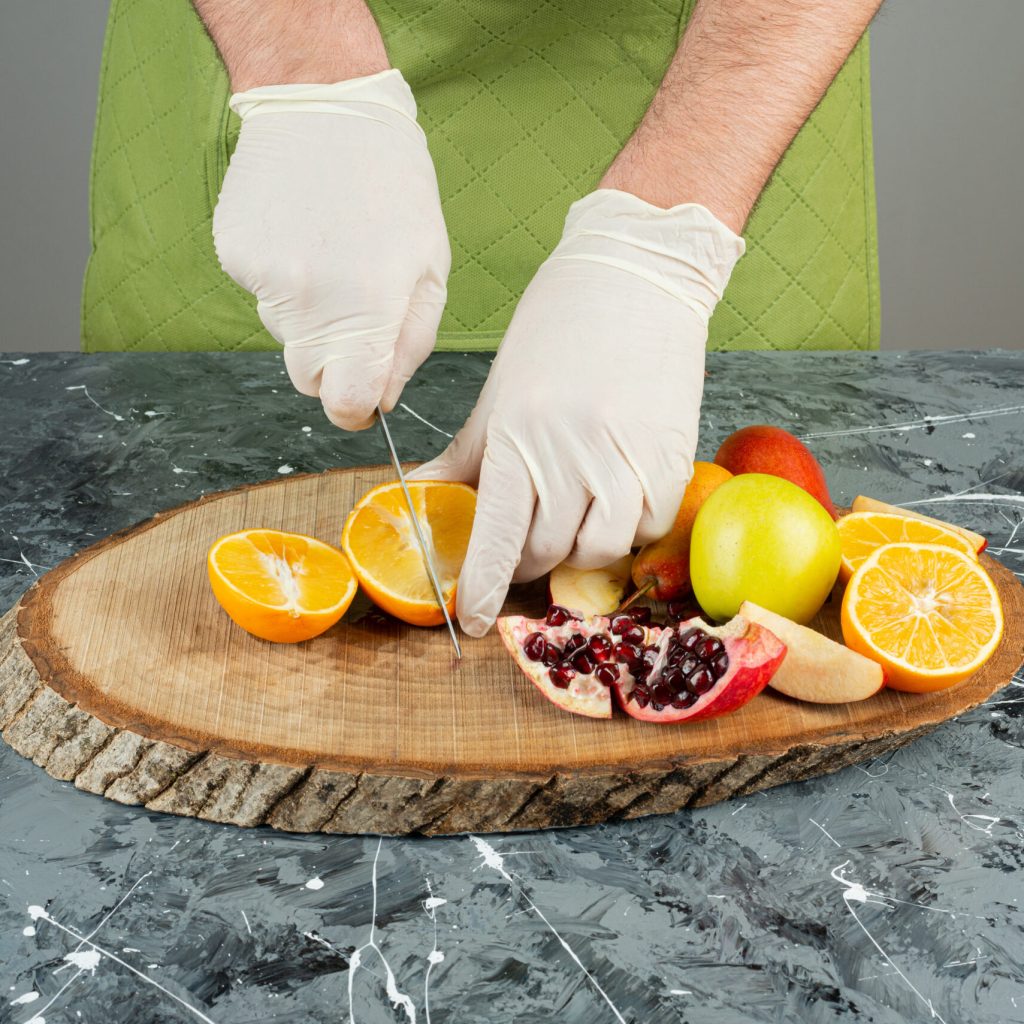 male hand in gloves cutting juicy orange on marble table